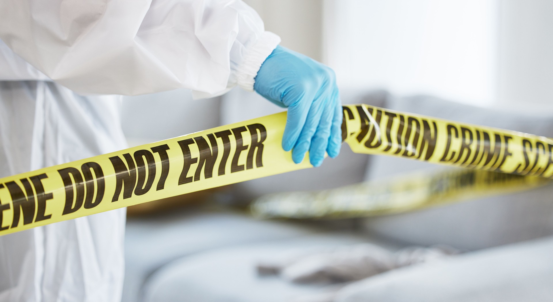Forensics, crime scene and tape with investigator hand in house lounge for investigation, research or safety. Medical, science and evidence with closeup of person for examination, police and security